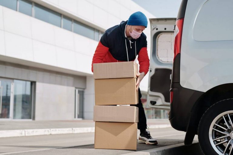 Person with mask on packing boxes in van