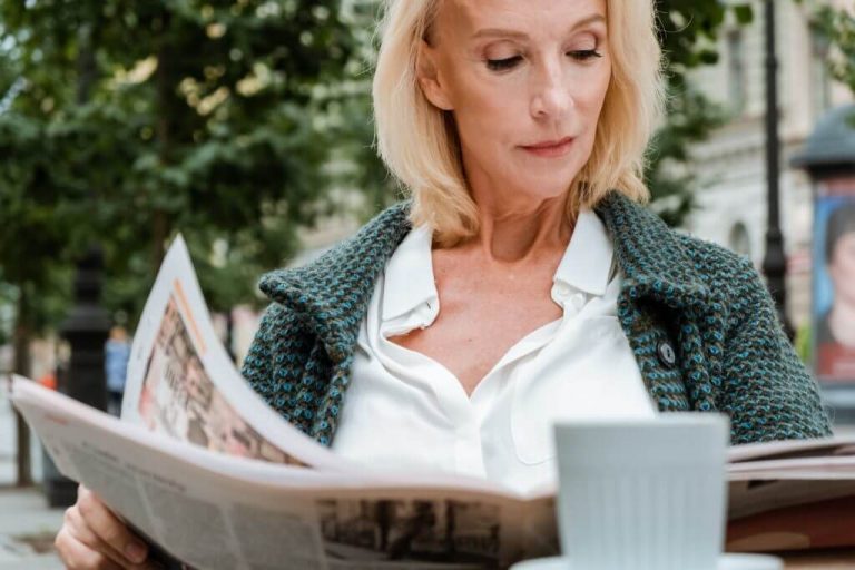 Senior reading over the news in a park